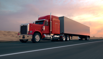 A truck driving on the highway at sunset